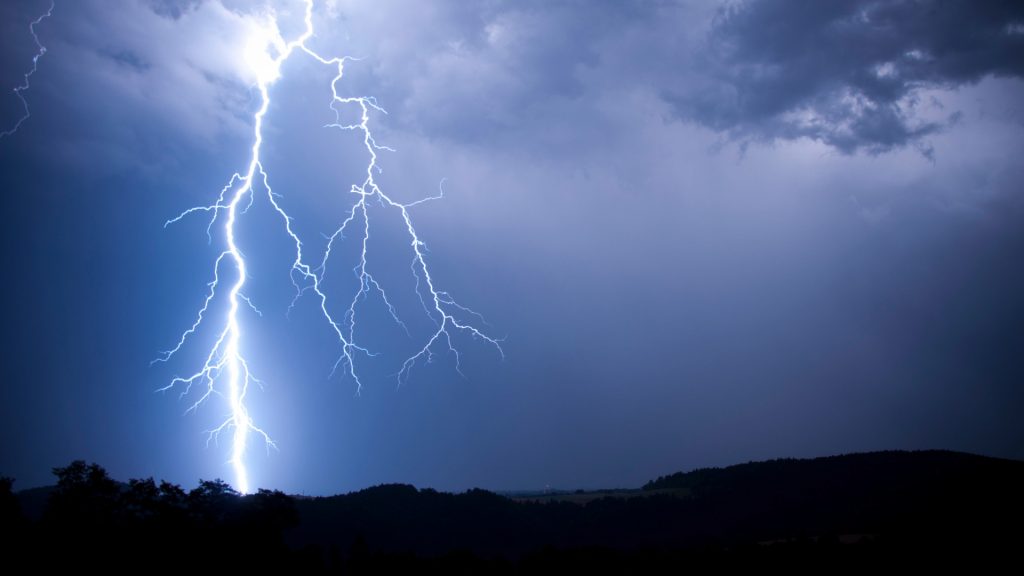 Beleuchtete Häuserzeile in der Nacht bei Gewitter.